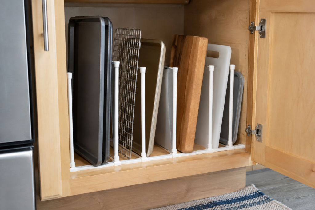 Removable vertical dividers organizing baking sheets, trays and cutting boards with different slot widths in a rental kitchen